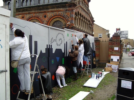 Members of the local community in Tower Hamlets painting a mural.