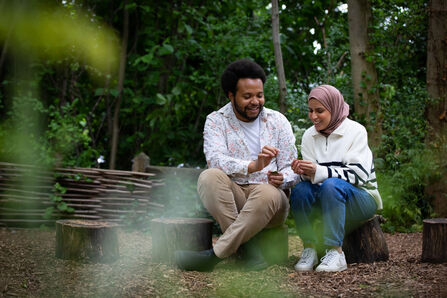 Two young people sat on a log in a woodland
