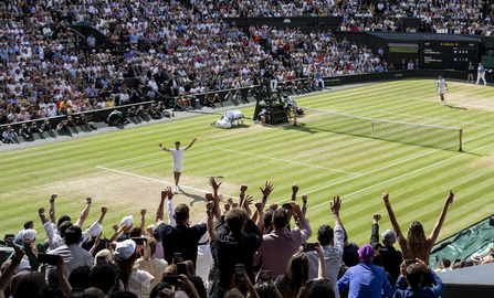 Image of winning tennis player on centre court celebrating with crowd