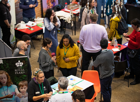 Room full of people, chairs and tables set out with paper and information banners at the Green Jobs Fair