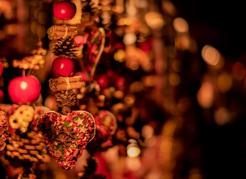 A close up of festive decorations made from pine cones, cinnamon and an embroidered heart