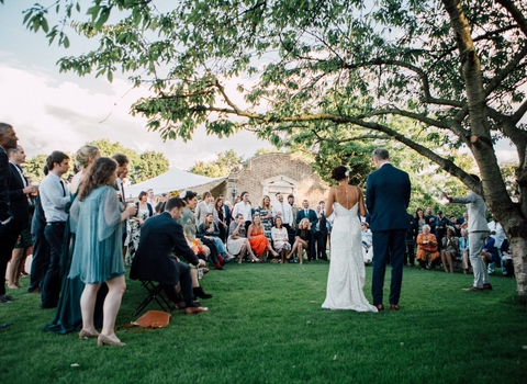 a couple get married surrounded by a semi circle of people looking on