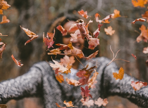 Woman throwing autumn leaves
