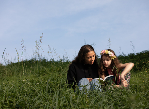 Two people sat on a hill reading