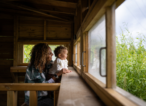 A woman and child looking out from a bird hide into the reedbed